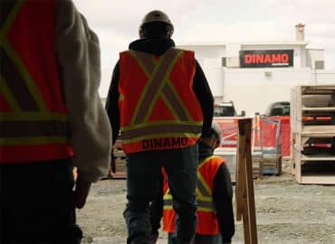 Des ouvriers du bâtiment portant des gilets de haute visibilité passent devant un chantier de Dinamo.